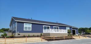 A two-story residential building with a balcony, a driveway, and a parking area. - Stunning waterfront home, beach, pools, pet friendly! (Long Neck)