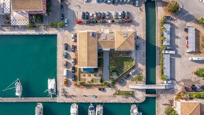 Eine Vogelperspektive auf einen Hafen mit vertäuten Booten, einem Parkplatz und einem Gebäude mit geneigtem Dach.