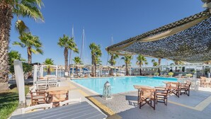 Ein Poolbereich mit Liegestühlen, einem Pool und Palmen.