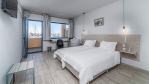 Ein Hotelzimmer mit Bett, Schreibtisch, Stuhl und einem an der Wand befestigten Fernseher.
