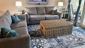 A living room with a grey sofa, a wicker coffee table, and a framed painting of sailboats on the wall. - SHORES OF PANAMA- 3RD FLOOR!
Perfect for a couple plus two kids in the bunkroom. (P C BEACH)