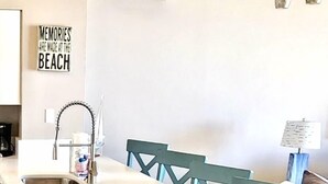 A modern kitchen with a central island, teal chairs, and a wall-mounted light fixture. - SHORES OF PANAMA- 3RD FLOOR!
Perfect for a couple plus two kids in the bunkroom. (P C BEACH)