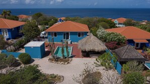 A coastal property with multiple blue buildings, a pool, and a thatched-roof structure. - Villa Despacito (Sint Willibrordus)