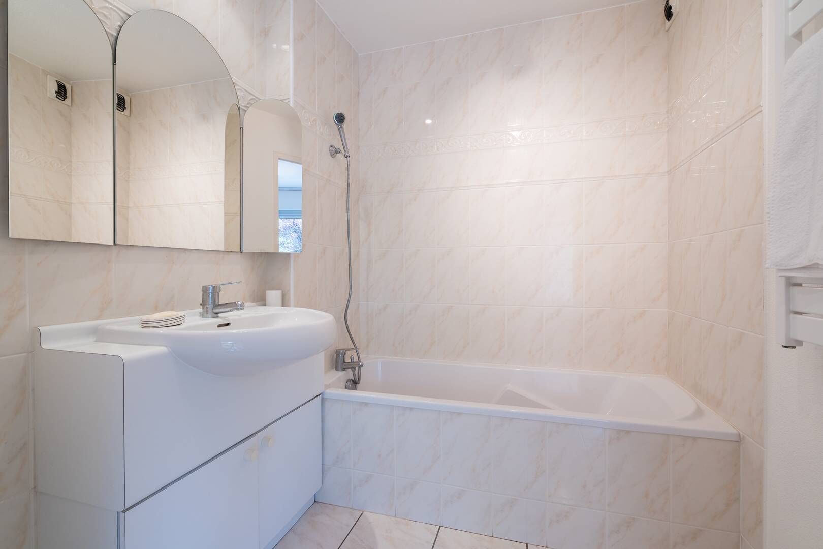 A modern bathroom with a white sink, mirror, and bathtub.