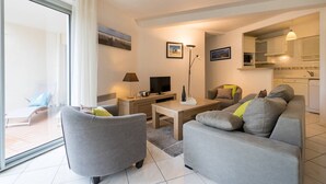 A modern living room with a sofa, armchair, TV, and a dining table. - Carnac - 3-room apartment - 69m² - Wifi (CARNAC)