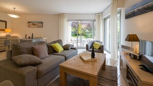 A modern living room with a sofa, a coffee table, and a dining area. - Carnac - 3-room apartment - 69m² - Wifi (CARNAC)