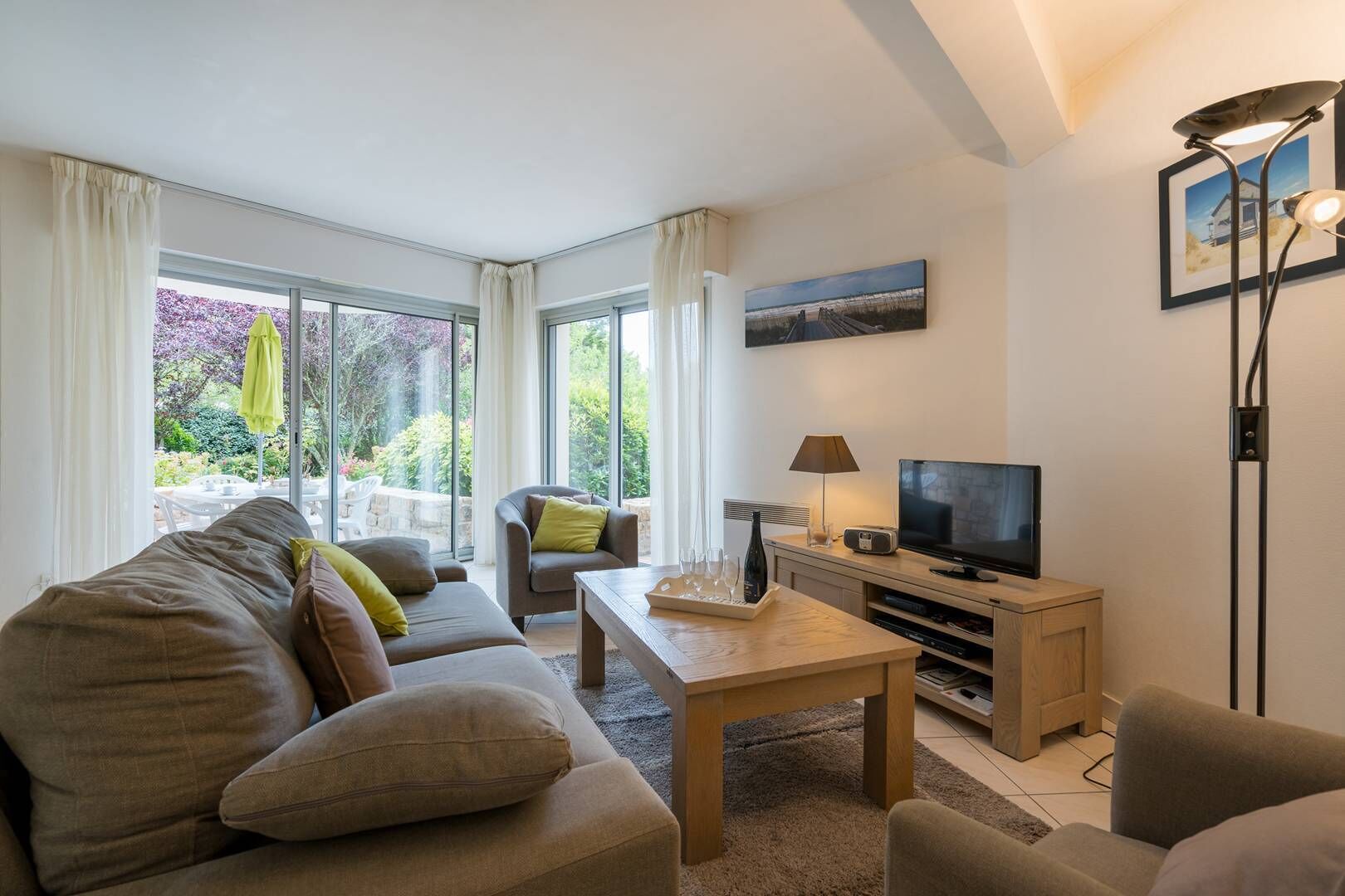 Een moderne woonkamer met een bank, fauteuils, een salontafel, een televisie en een eethoek met een tafel en stoelen.
