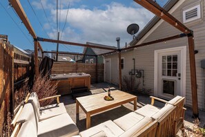 Un patio cubierto con un jacuzzi, mobiliario de madera y un pérgola de madera.