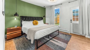 A bedroom with a bed, bedside tables, a chandelier, a view through a door, and a green wall. - Pine Street Retreat | 1BR Hot Tub Home, Dog Door, Walk to Main St | Leadville (Leadville)