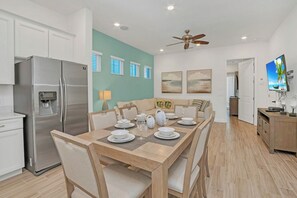 Una cocina moderna con un refrigerador de acero inoxidable, una mesa de comedor para cuatro personas y un ventilador de techo.