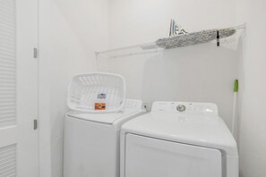 A laundry area with two white washing machines and a plastic laundry basket.