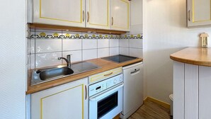 A compact kitchen with white cabinets, a sink, a stove, and a dishwasher. - Quiberon - 2rooms + duplex - 38m² - near beach (QUIBERON)