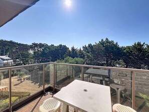 A balcony with a table and chairs, overlooking a forested area.