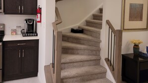 Un escalier avec une rampe en bois et des marches recouvertes de moquette, menant à un palier.