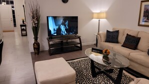 Un salon comprenant un téléviseur, un canapé, une table basse et un vase décoratif.