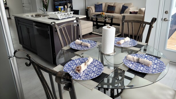 Une cuisine moderne avec un coin repas comprenant une table et des chaises en verre, un canapé et un tableau accroché au mur.
