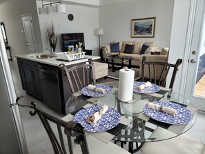 A modern kitchen with a dining area featuring a glass table and chairs, a sofa, and a painting on the wall. - Comfy 3Bdrm home near Hyde Park Mall/Western Uni (London)