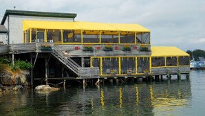 A waterfront building with a yellow roof and two levels of windows. - Western Mountain Townhouse (Southwest Harbor)