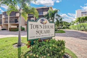 A sign for Town House Square with a view of a multi-story building in the background.