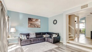 A living room with a sectional sofa, a rug, a wall clock, and a painting. - Paradise - quiet, clean, upgraded condo; walk to beach (Marco Island)