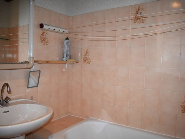 A bathroom with a sink, a mirror, a shower, and a shelf with toiletries. - Studio cabin mezzanine with parking, Pyrenees view (Font-Romeu-Odeillo-Via)