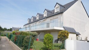A modern residential building with a balcony, a fenced garden, and a clear sky. - Etel - 2-room apartment - 40m² - Wifi - 3* (ETEL)