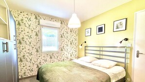 A bedroom with a bed, a window, a wall-mounted air conditioner, and a door. - Etel - 2-room apartment - 40m² - Wifi - 3* (ETEL)