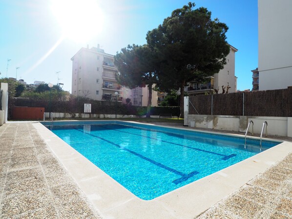 Une piscine à l’eau d’un bleu limpide, entourée d’une terrasse bordée de galets.
