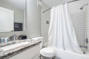 A bathroom with a white sink, a toilet, and a shower with a white curtain.