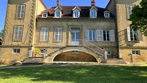 Un bâtiment historique doté d’une arche centrale, de nombreuses fenêtres avec volets et d’un toit recouvert de tuiles.
