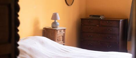 Un dormitorio con cama, cómoda, lámpara y espejo en la pared.