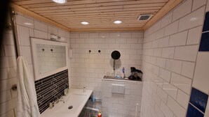 A modern bathroom with white tiles, a wooden ceiling, a sink, a mirror, and a toilet. - 2 Bed Retreat - Sleeps 4 - Pets - Parking - Wifi (Luleå)