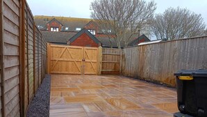 A backyard with a wooden deck, a wooden fence, and a house in the background. - Fisherman's-Terrace (Tardis) Old RNLI & Crabbing Area Free Secure Parking (Poole)