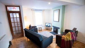 A living room with a sofa, a television, and a fireplace. - Fisherman's-Terrace (Tardis) Old RNLI & Crabbing Area Free Secure Parking (Poole)