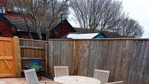 A patio with a wooden table and chairs, surrounded by a wooden fence and a wooden deck. - Fisherman's-Terrace (Tardis) Old RNLI & Crabbing Area Free Secure Parking (Poole)