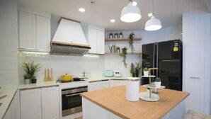 Une cuisine moderne avec des meubles blancs, un îlot central en bois et des luminaires suspendus.