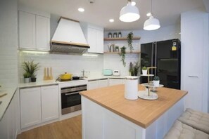 Eine moderne Küche mit weißen Schränken, einer Holztheke und Pendelleuchten.