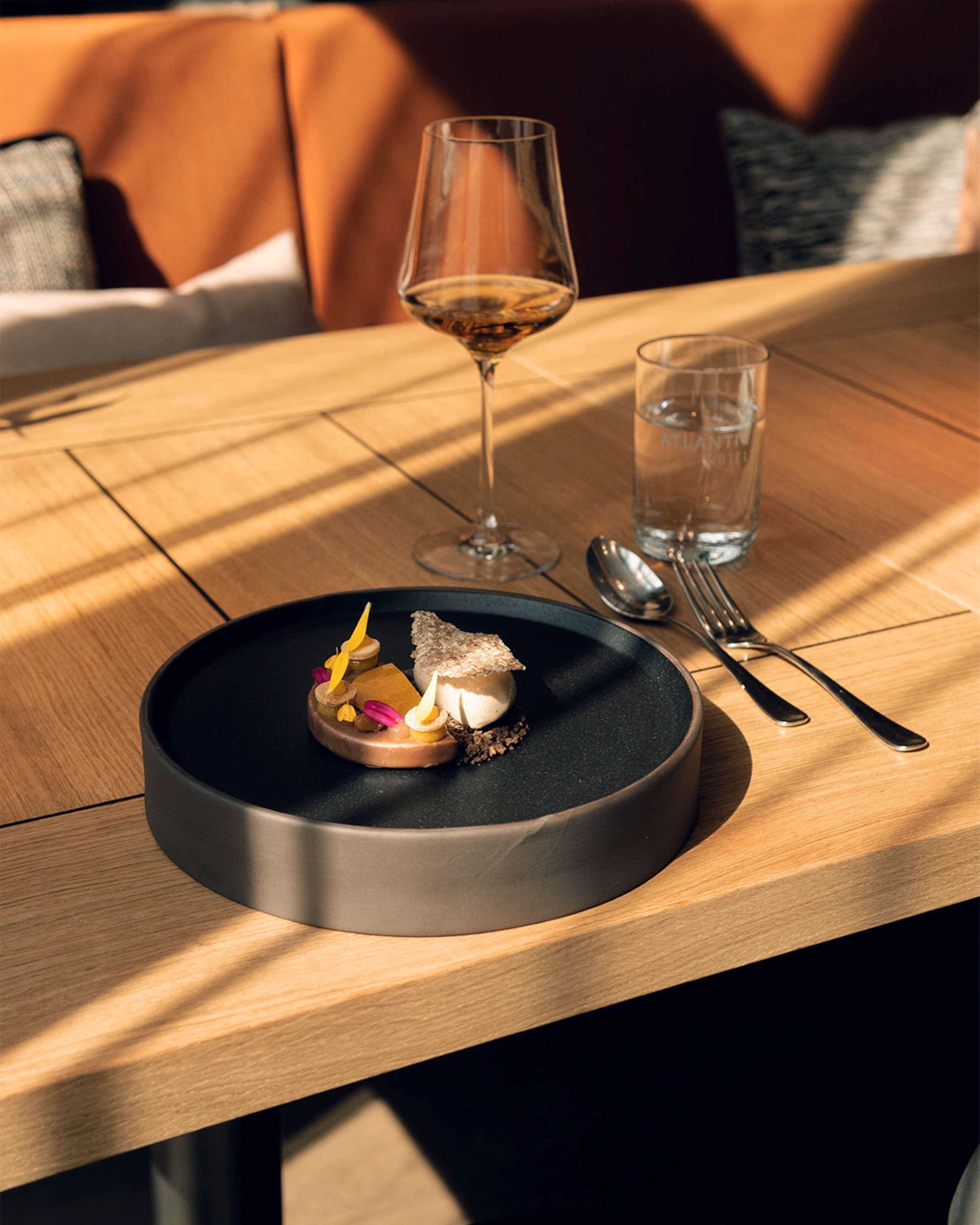 A dining table with a dessert plate, a wine glass, and a water glass.