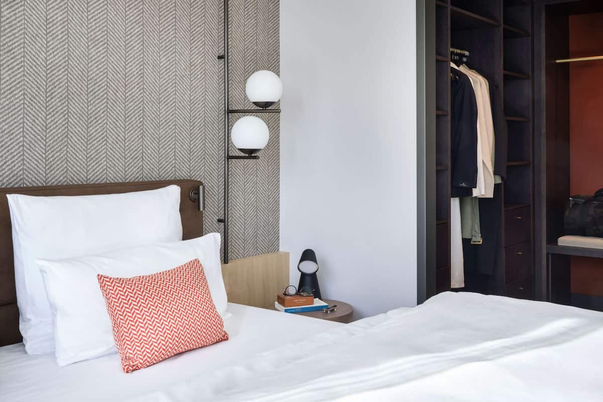 A hotel room with a bed, a nightstand, a lamp, and a wardrobe.