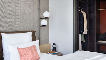 Ein Hotelzimmer mit Bett, Nachttisch, Lampe und Kleiderschrank.