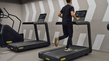 Un gimnasio con cintas de correr y una máquina de escaleras.