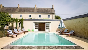 Ein Swimmingpool mit Liegestühlen und einem Gebäude im Hintergrund.