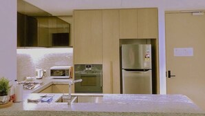 Uma cozinha moderna com eletrodomésticos embutidos, incluindo micro-ondas, forno e geladeira.