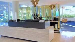 Uma área de recepção moderna com balcão, divisória de vidro e área de estar com cadeiras.