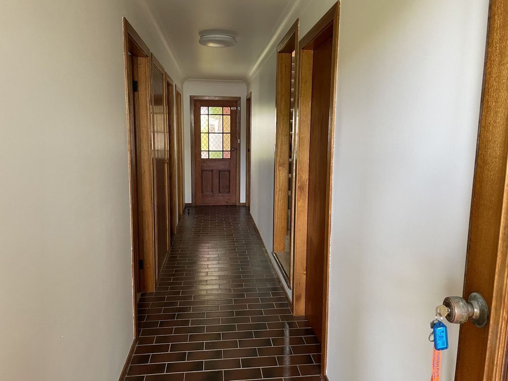 A hallway with wooden doors and a tiled floor leading to a door with a window.