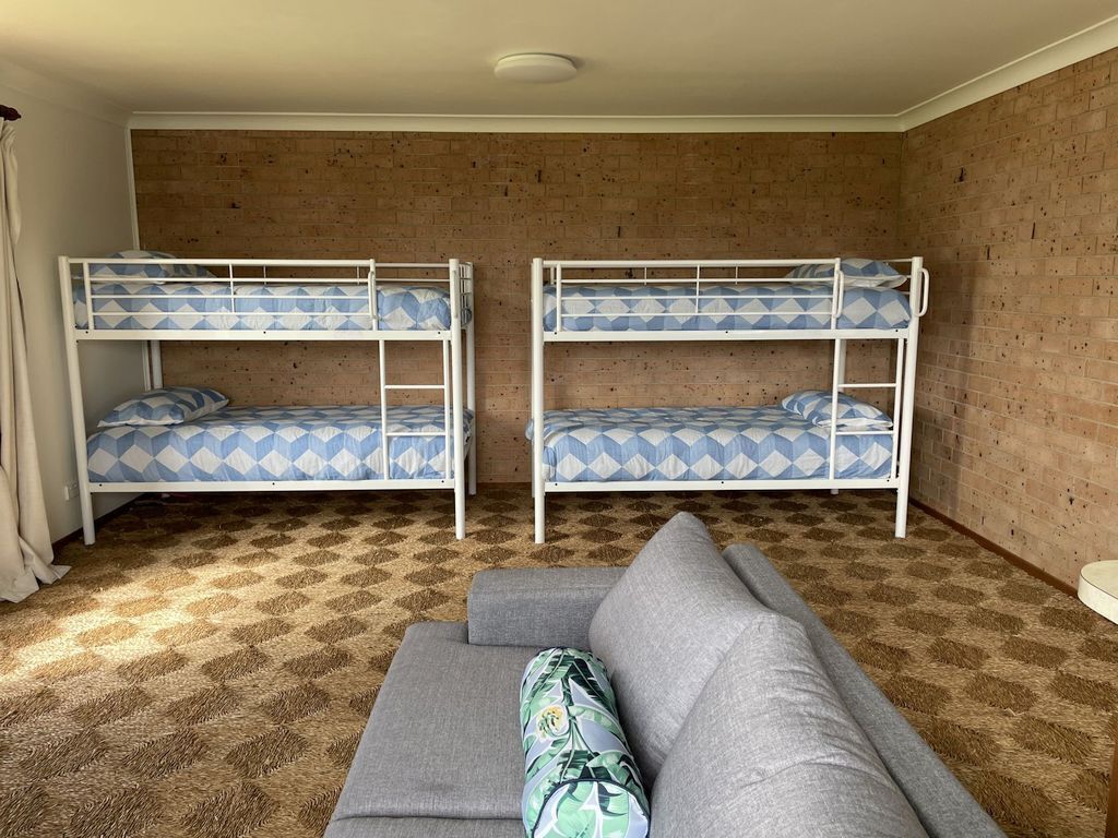 Une pièce avec deux lits superposés, un canapé gris et un tapis à motifs.