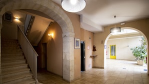 A spacious hallway with a staircase, a large archway, and a potted plant. - APPT 11 de la MAISON D'ANTONIN (Nîmes)