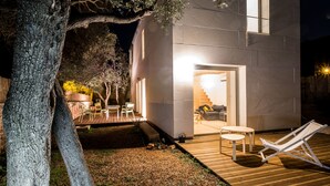 A modern house with a wooden deck, outdoor seating, and a staircase leading to an interior room. - Architect-designed VILLA Sleeps 6/7. 150 m from beaches (Bandol)