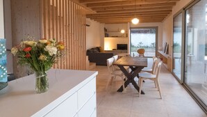 A modern kitchen with a dining area, wooden ceiling beams, and a large window providing a view of the outdoors. - Architect-designed VILLA Sleeps 6/7. 150 m from beaches (Bandol)