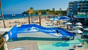 A water park with a wave pool, palm trees, and a beach in the background. - Acogedor apartamento a 100 metros de la playa (Palmanova)